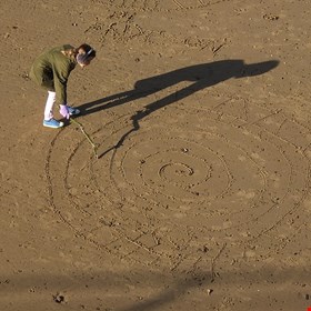 Drawing with a stick and with her shadow!